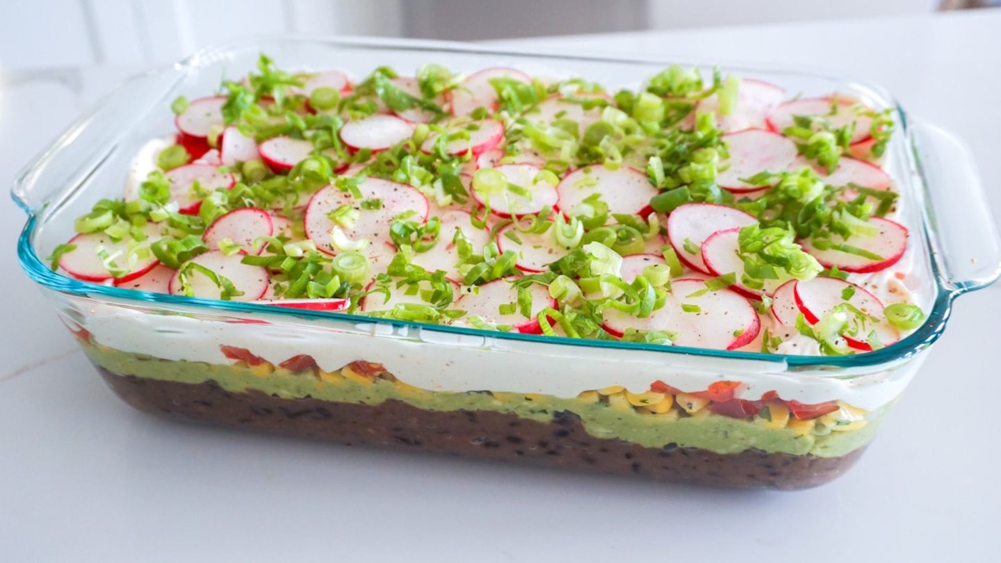 7 layer dip in a glass casserole dish on a white counter
