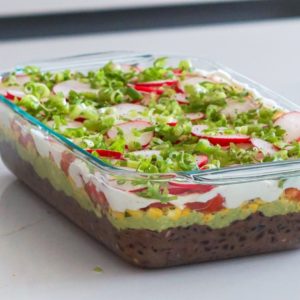 vegan seven layer dip in a glass casserole dish on a white counter