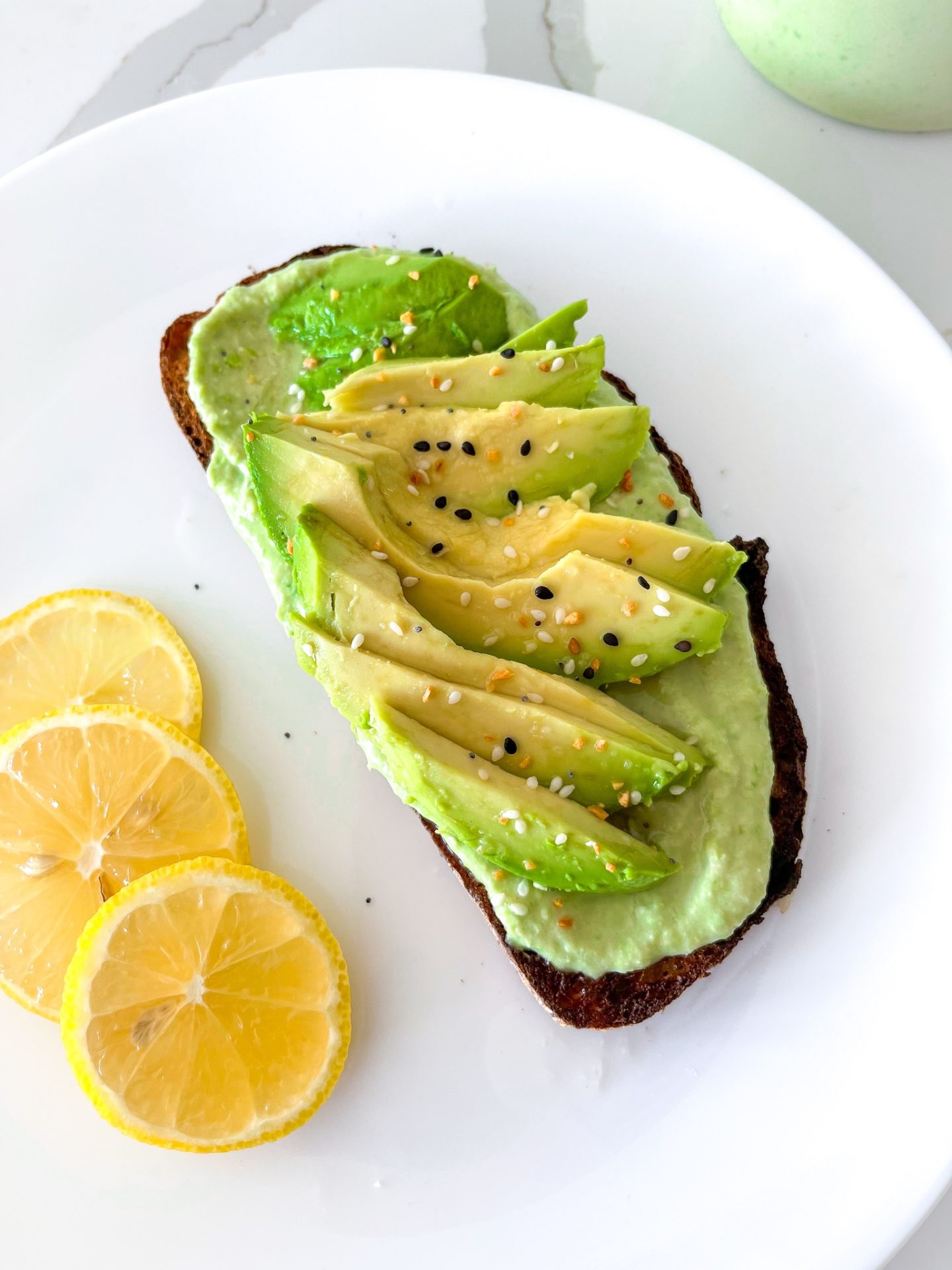 toast with hummus and avocado on a white plate 