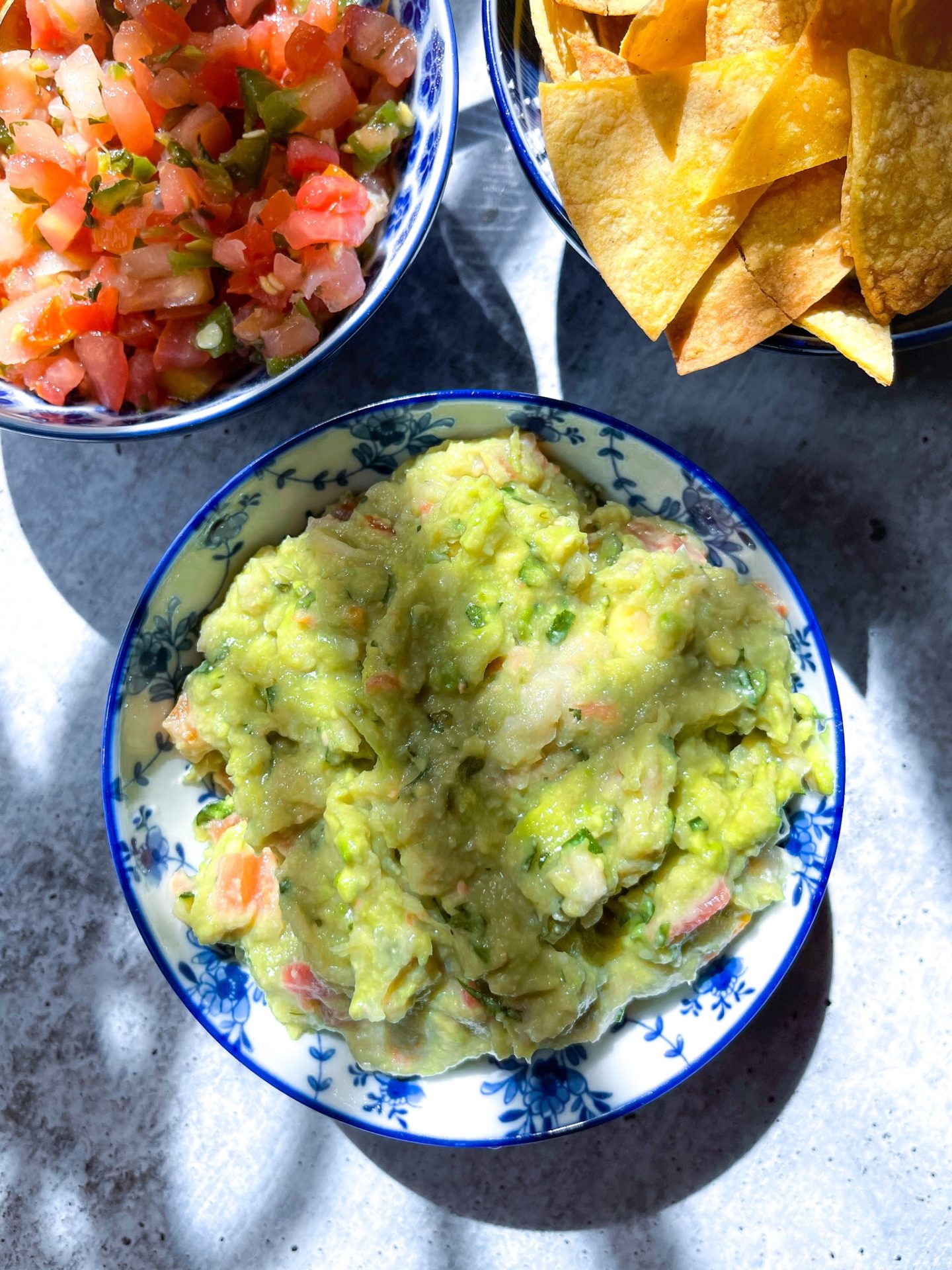 guacamole, salsa, and tortilla chips in blue bowls 