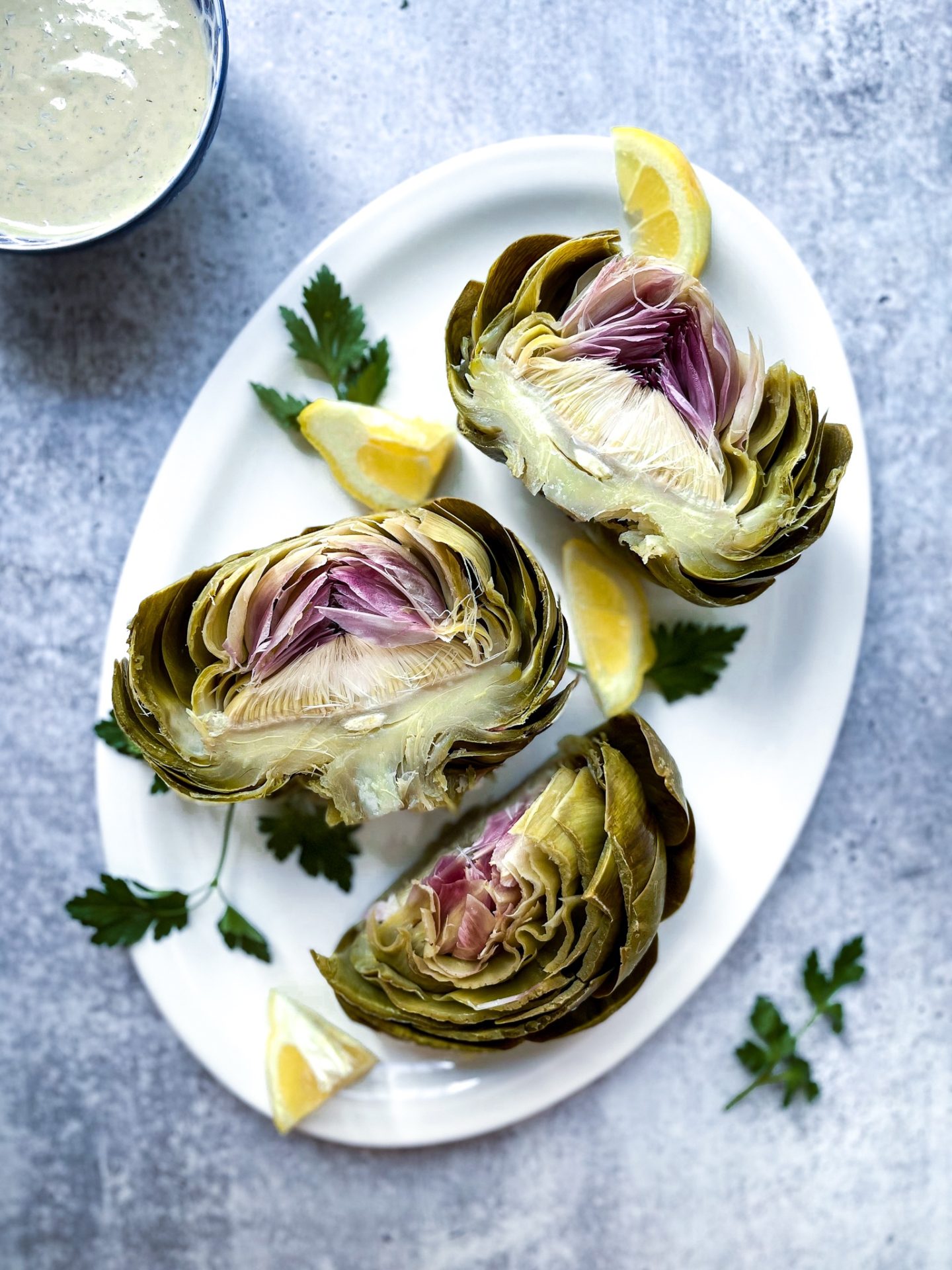 steamed artichokes on a white plate with tahini sauce