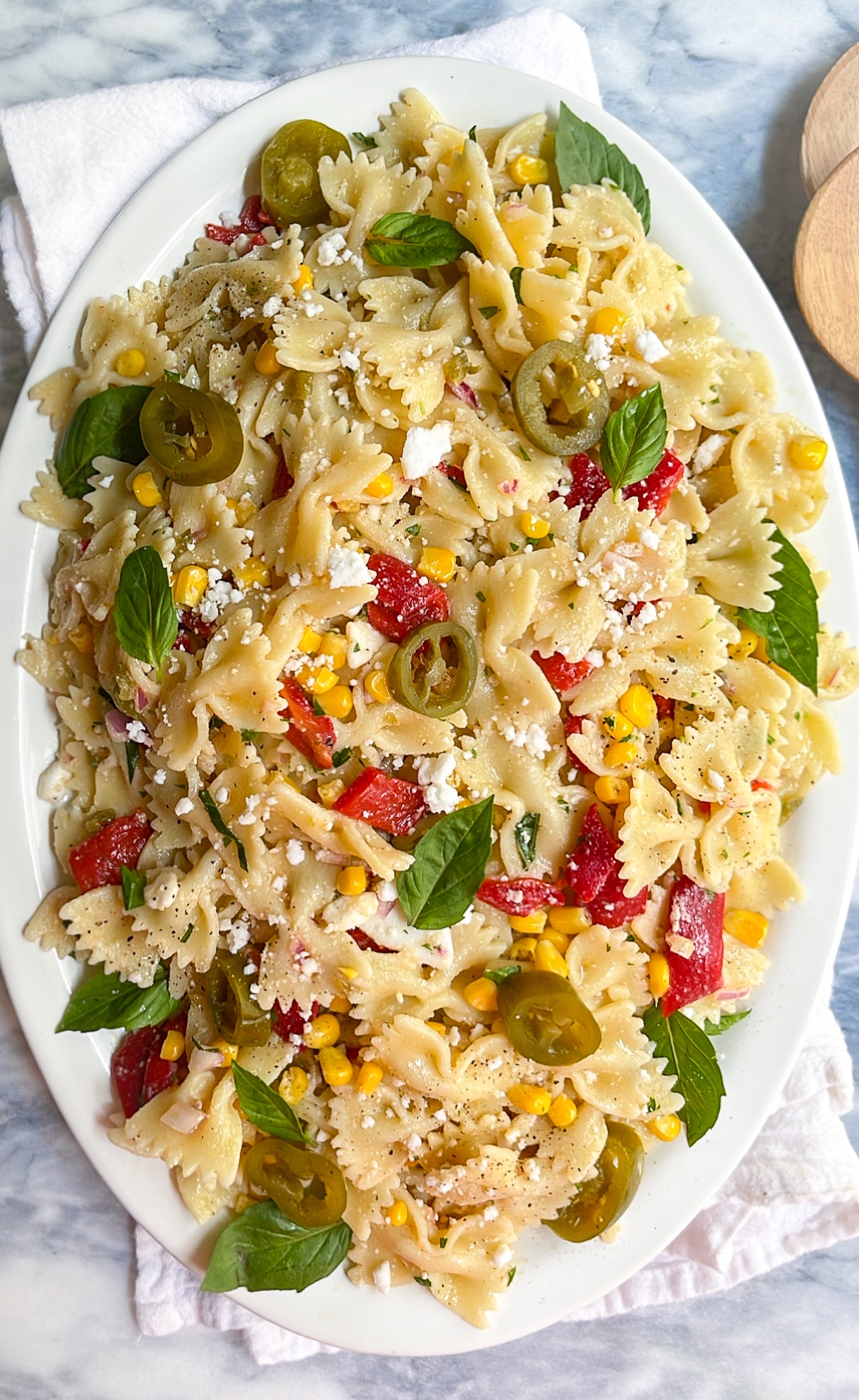 pasta salad with basil and red peppers on a white plate