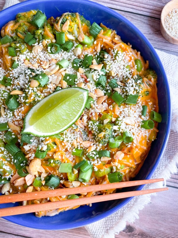 peanut noodles with scallions and lime on a blue plate