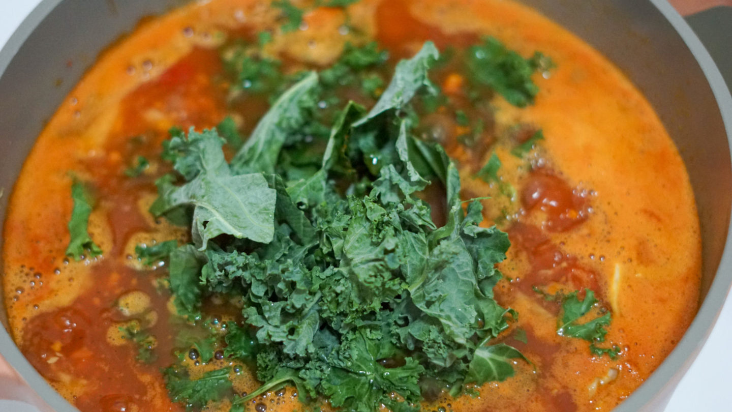 tomato broth with kale and white beans in a stockpot