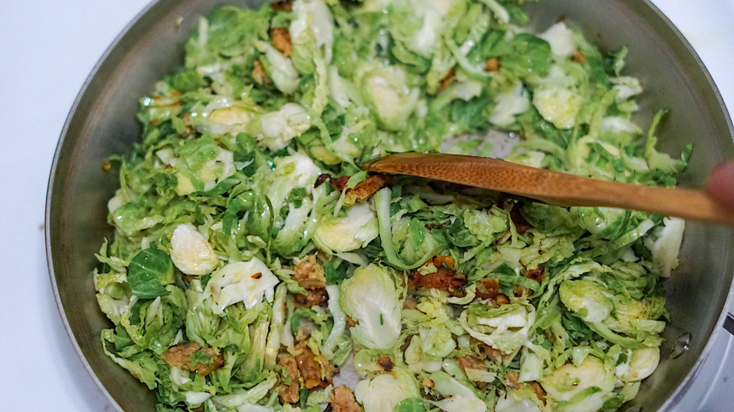 shredded Brussels sprouts and tempeh bacon in a pan