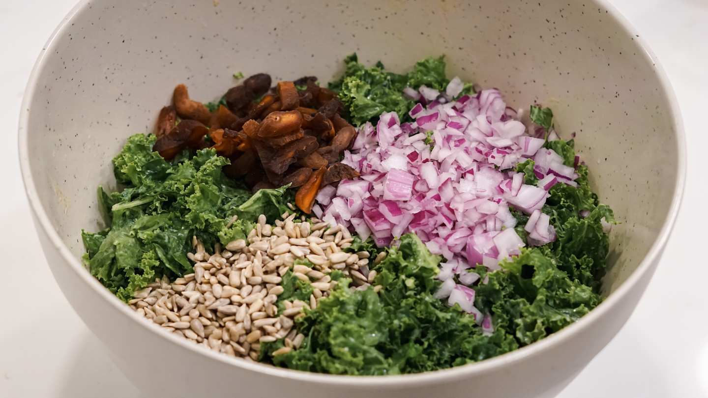Crispy chickpea and kale salad with apricots, sunflower seeds, red onions, and creamy tahini dressing in a bowl