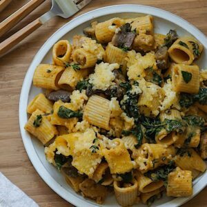 pumpkin pasta with kale and mushrooms served on a white plate