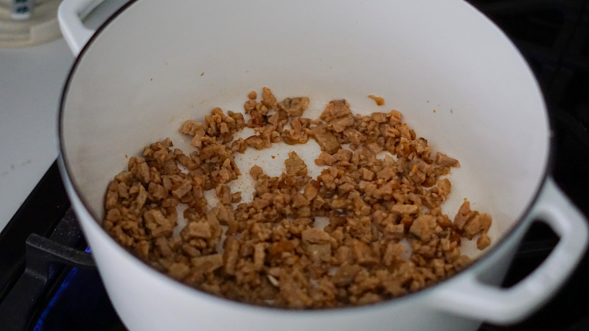 cooking vegan bacon in a large white pot