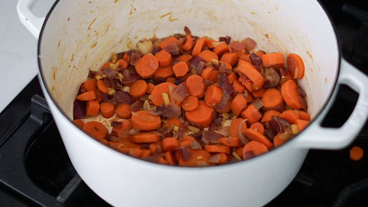 cooked carrots, onions, and ginger in a white pot